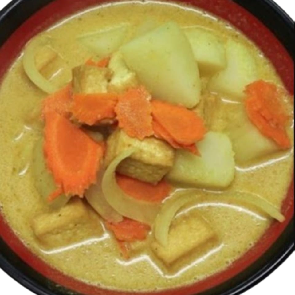A bowl of Pho Lena's Vietnamese curry with tofu, carrots, and potatoes in a rich yellow broth.